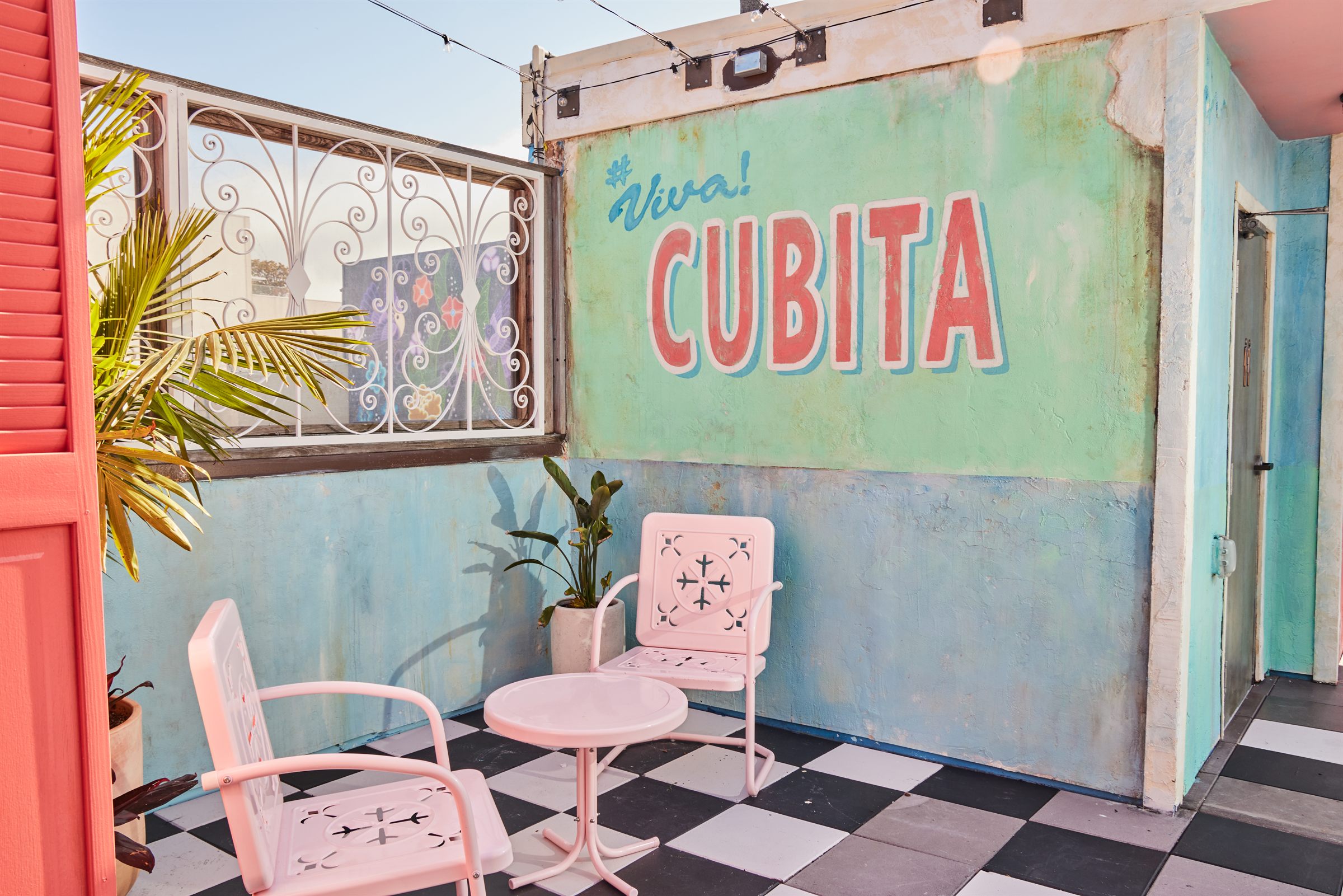 Colorful Cubita patio with pastel mural, checkerboard floor, and pink seating